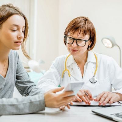 Ärztin und Patienten schauen auf ein Handy