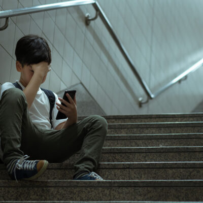Trauriger Junge mit Handy alleine