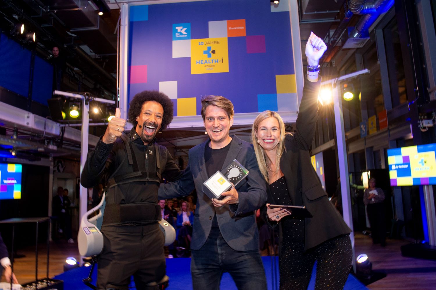 „Health-i Persönlichkeit des Jahres“ Alexander Leutner (Mitte), CEO & Co-Founder der Cellbricks GmbH mit den beiden Moderatoren des Abends, Flo Akinbiyi und Lara Sophie Bothur 