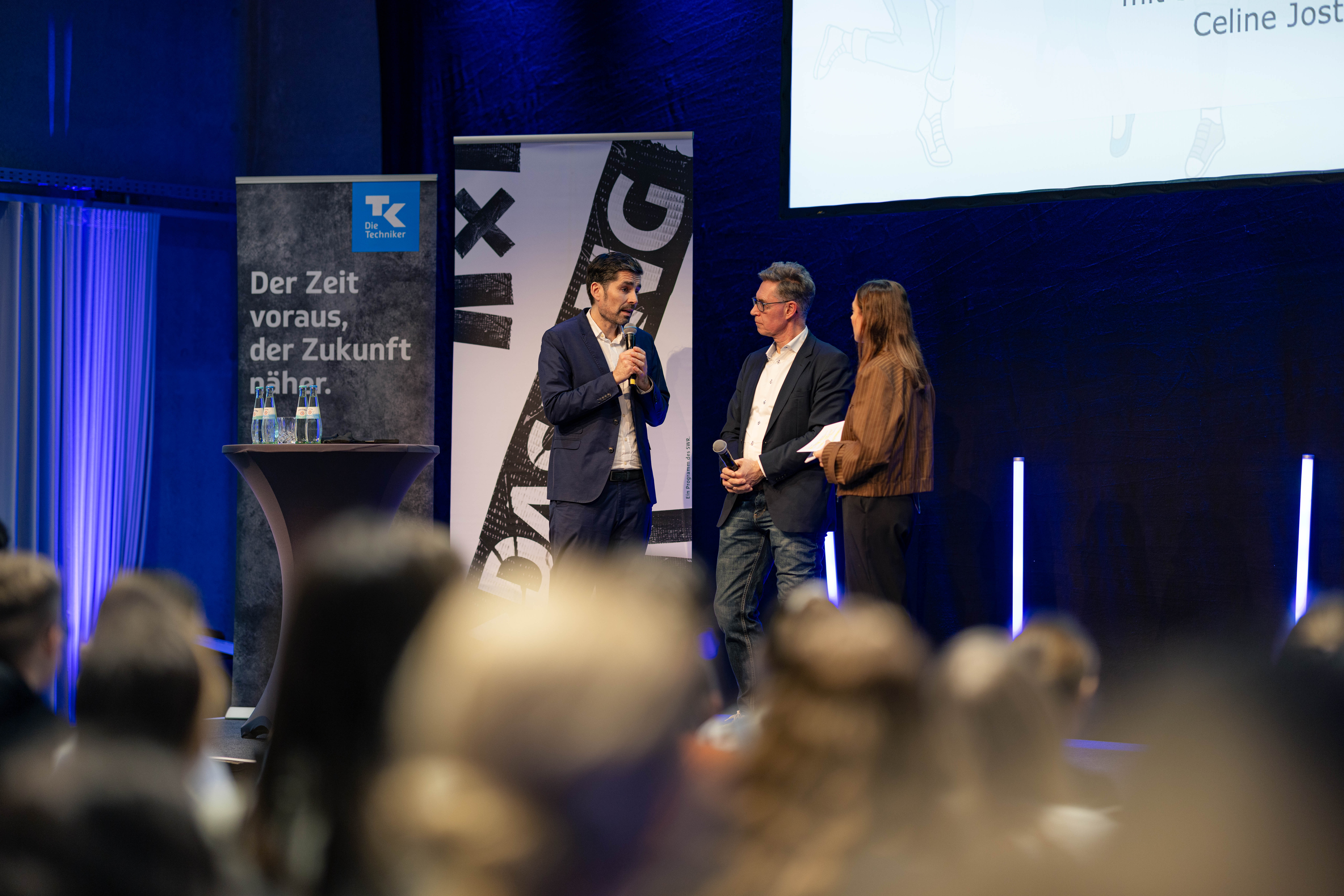 Landesbildungsminister Sven Teuber, Jörn Simon (Leiter der TK-Landesvertretung Rheinland-Pfalz) und Moderatorin Celine Jost